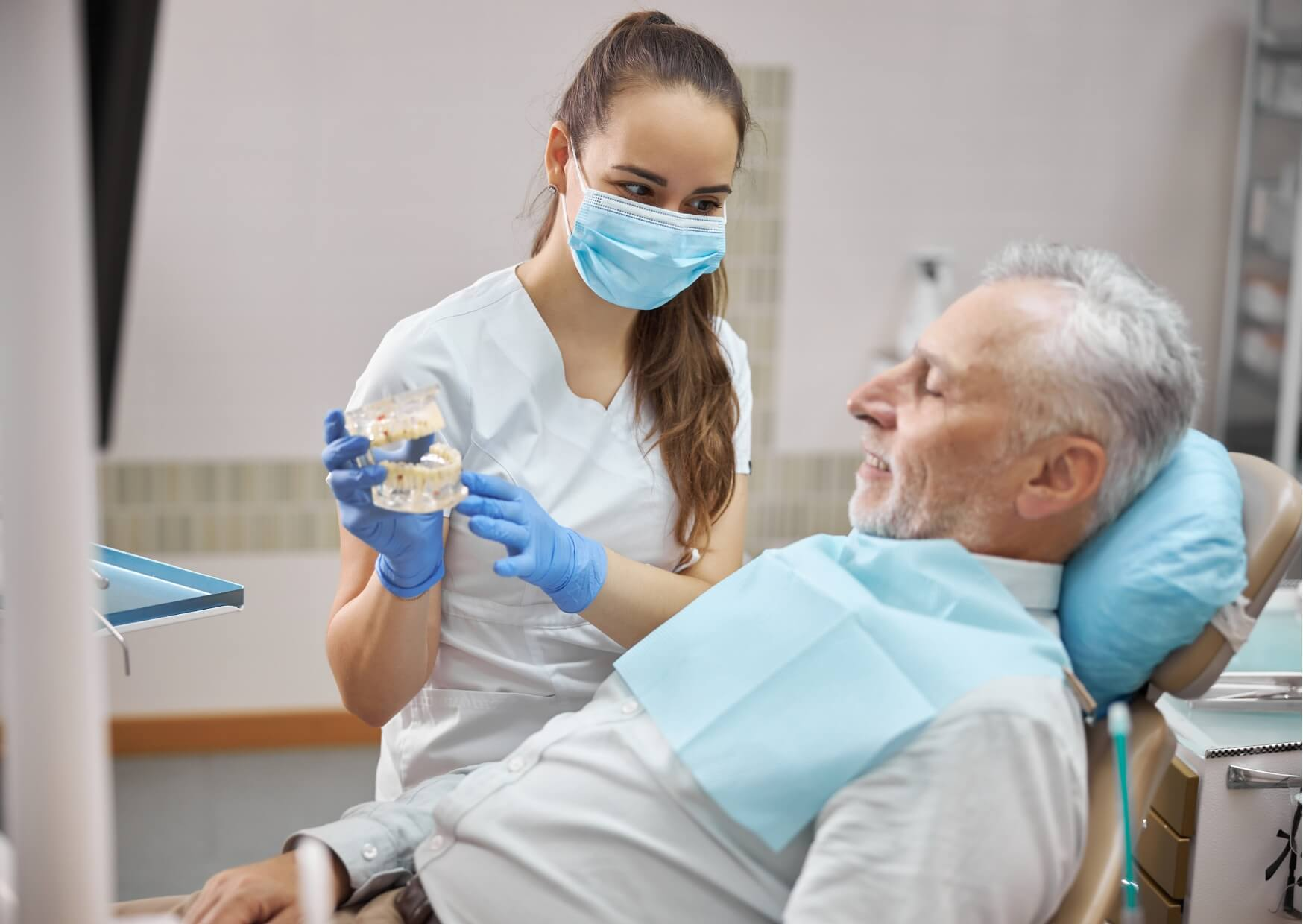 Dental professional discussing tooth replacement options with an older patient, highlighting dental implant candidacy later in life.