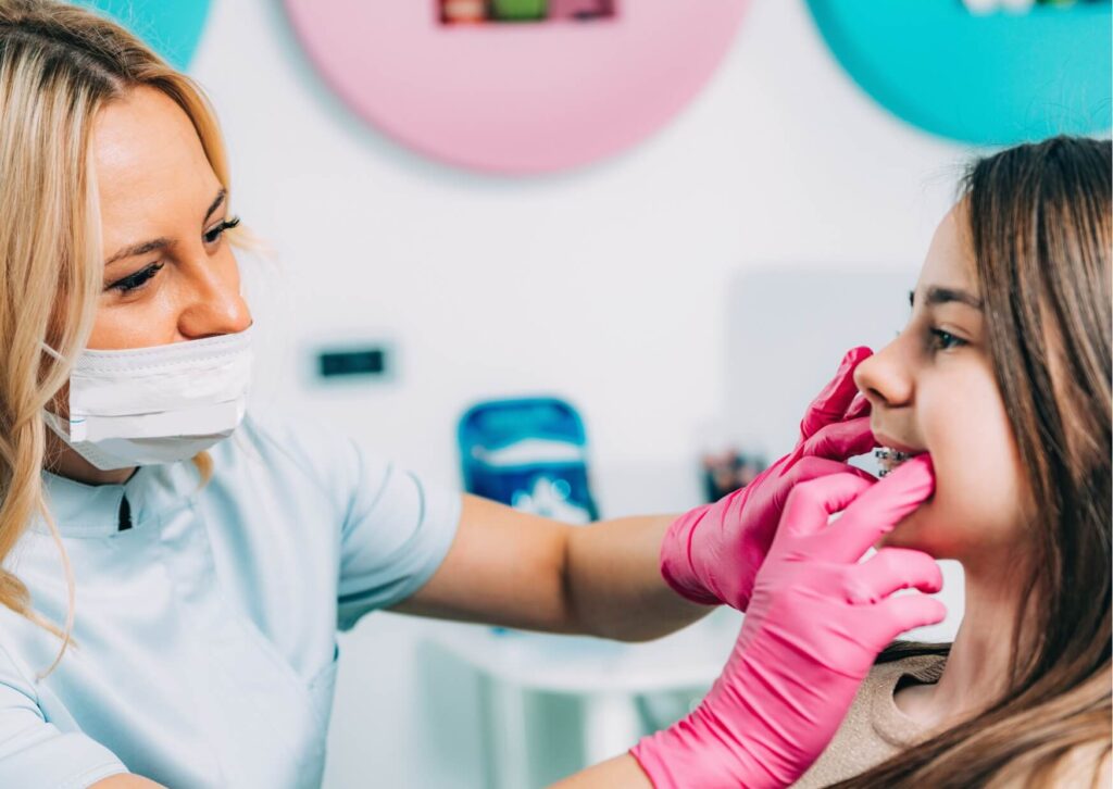 Orthodontist examining a teenager's braces while discussing which types of candy are safer to eat and which can damage brackets and wires.