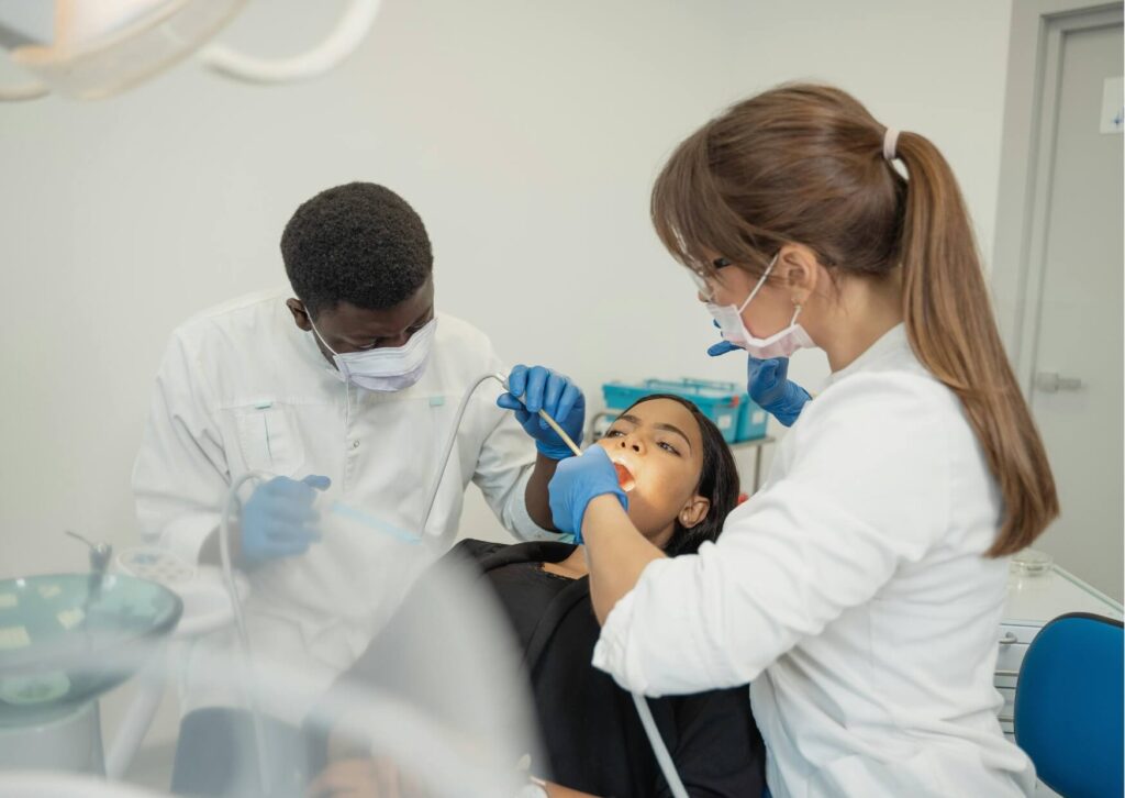 Dentists examining a patient's teeth during a dental exam to identify what tooth decay looks like and assess cavities before treatment.